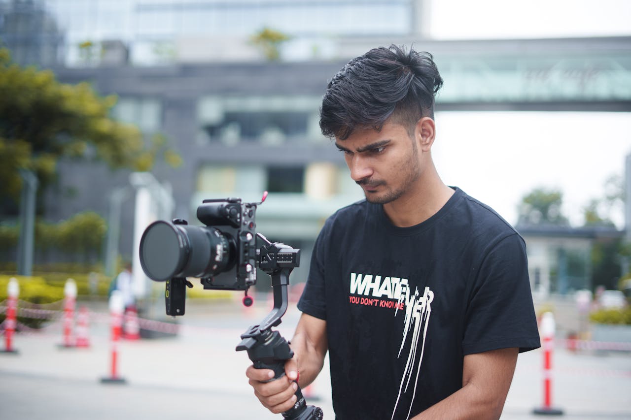A young filmmaker using a gimbal and camera setup outdoors for dynamic video shooting.