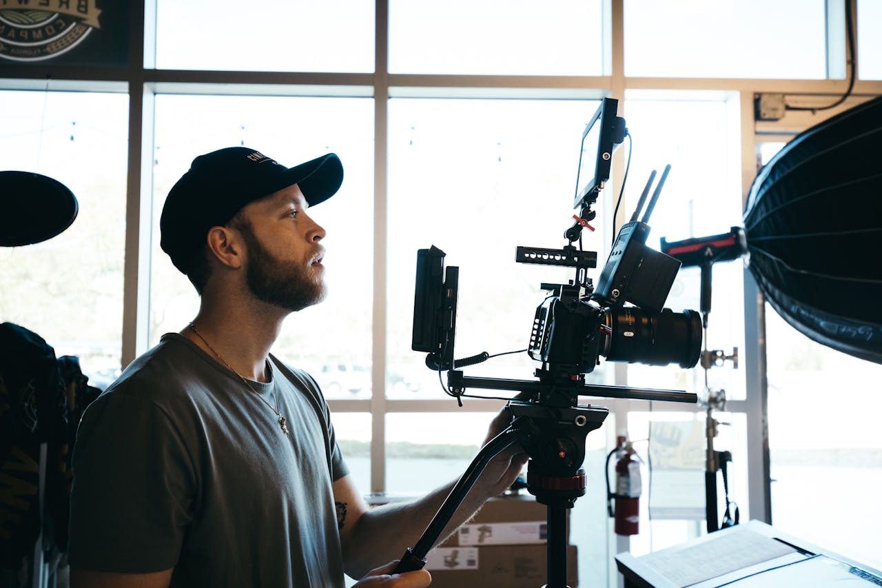 A focused filmmaker operates a professional camera rig indoors, surrounded by equipment.